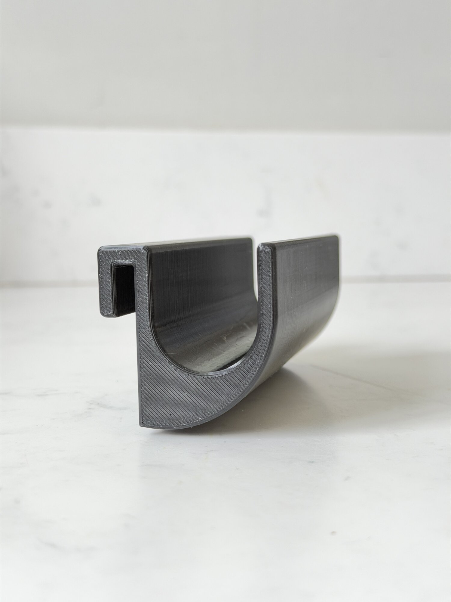 The Caddy Hook — a curved PETG channel with a square tab that grips the bin rim